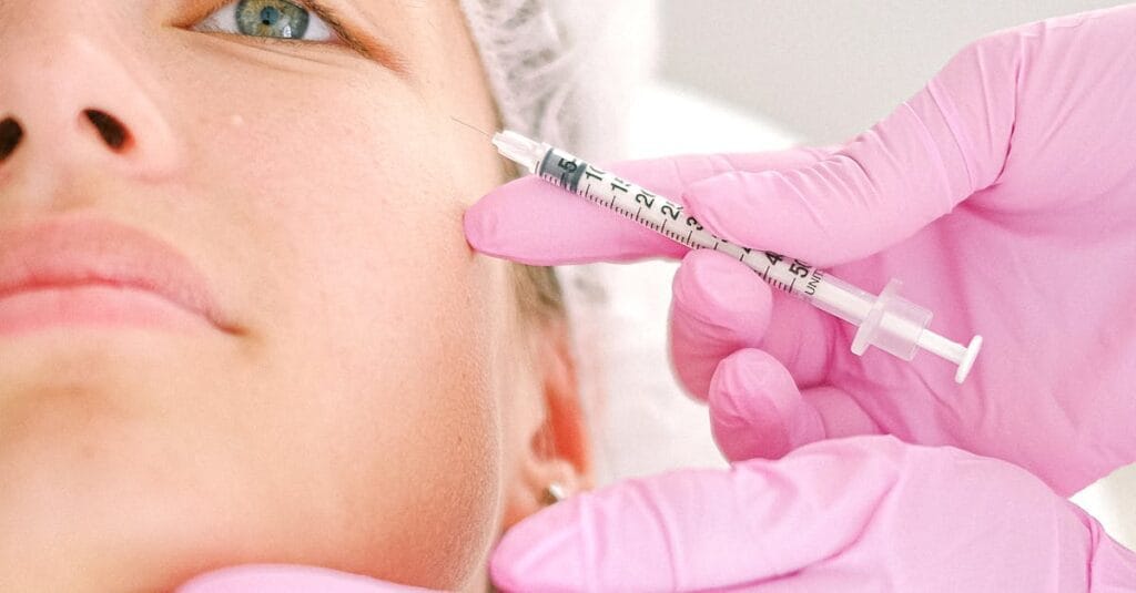 Close-up of a beautician administering facial injection treatment to a woman in a clinical setting.