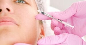 Close-up of a beautician administering facial injection treatment to a woman in a clinical setting.